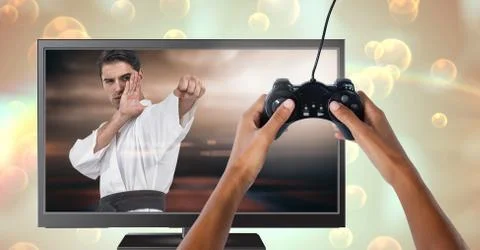 Hands holding gaming controller  with martial arts fighter player on television Stock Photos