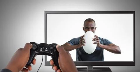 Hands holding gaming controller  with rugby player on television Stock Photos