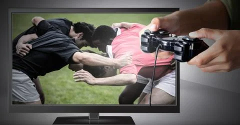 Hands holding gaming controller  with rugby players on television Stock Photos