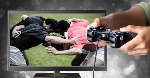 Hands holding gaming controller  with rugby players on television Stock Photos