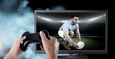 Hands holding gaming controller  with rugby player on television Stock Photos