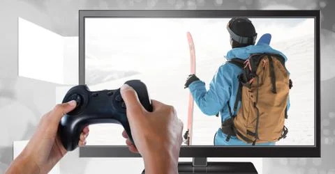 Hands holding gaming controller  with ski man on television Stock Photos