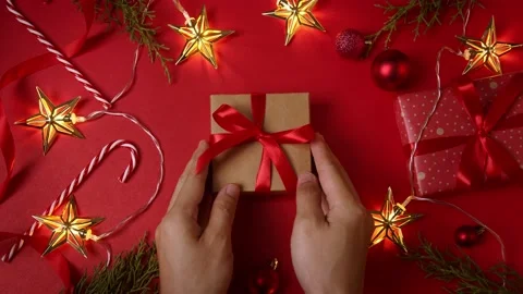 Hands holding gift box with bow on the red background of Christmas New Year d Stock Footage 220788130
