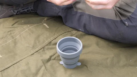 Hands Holding Gray Cup on Outdoor Fabric 库存影片 334047702