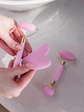 Hands holding jade roller and gua sha tools Photos