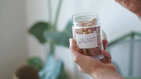 Hands holding a jar of walnuts in a kitchen Stock Footage 334908451