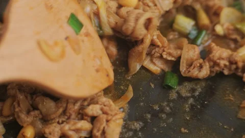 Hands holding a ladle stir-frying kimchi and kurobuta pork in a wok in kitchen. Stock Footage 242552191