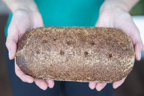 Hands holding a loaf of bread close-up. Homemade piece of rye bread. Stock Photos