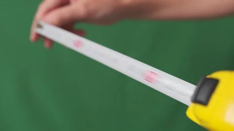 Hands holding measuring roulette pulling out metal tape to measure distance Stock Footage 253971325
