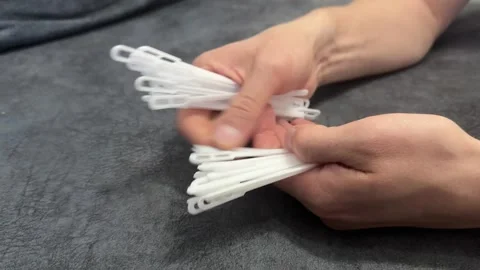 Hands holding multiple white plastic clothing tags. Packaging or retail concept, Stock Footage 336524212