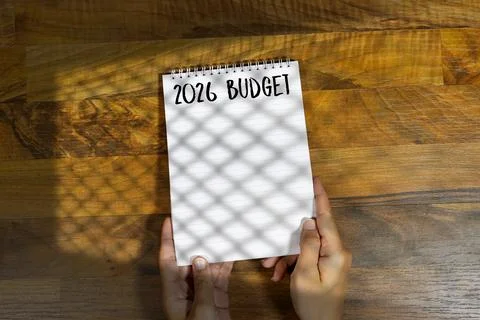 Hands Holding a Notebook With '2026 Budget' Written on a Wooden Table Stock Photos