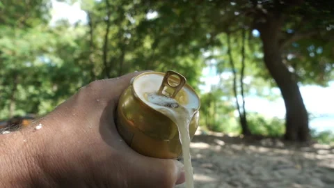 Hands holding an open foamy can of beer in slow motion of a natural landscape Video stock 137027307