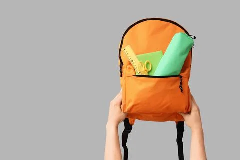 Hands holding an orange backpack filled with school supplies, back to school  Stock Photos
