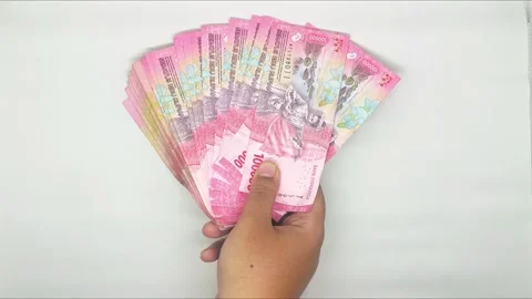 Hands holding out stack of Indonesian banknotes in the 100000 denomination Video stock 302318970