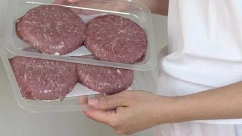Hands holding package with raw beef patties in kitchen setting, retail and food Stock-Footage 333775566