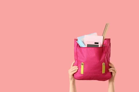 Hands holding a pink school backpack filled with various school supplies on a Stock Photos