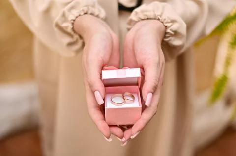 Hands holding pink wedding ring box, symbolizing love, commitment, and new .. Stock Photos