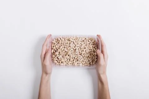 Hands holding a plastic container full of almonds on white background Stock Photos