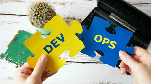 Hands holding puzzle with Dev and Ops words near laptop and motherboard. DevOps  Stock Footage 122418346