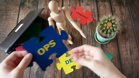 Hands holding puzzle with Dev and Ops words near laptop and motherboard. DevOps  Stock Footage 123145830