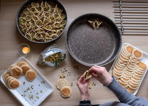 Hands holding Qatayef filled with chocolate and topped with pistachios on a.. Stock Photos