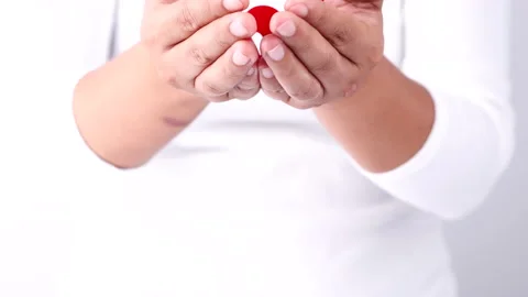 Hands holding red aids awareness ribbon on white background Stock Footage 164147652