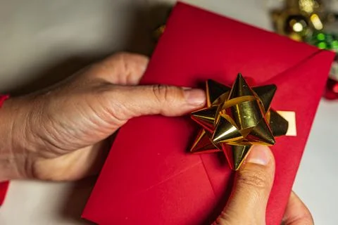 Hands Holding Red Christmas Envelope with Gold Bow Stock Photos