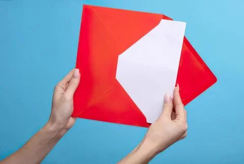 Hands holding red envelope with white paper on blue background Stock Photos