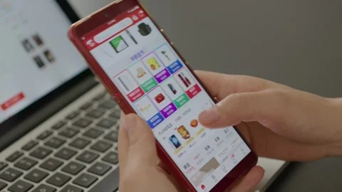Hands Holding Red Smartphone Browsing E-commerce App in Office Stock Footage 336528116