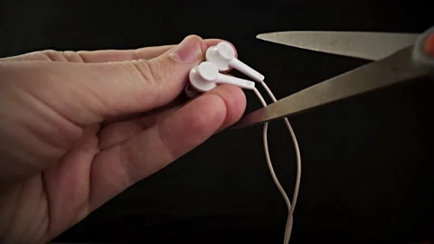 Hands holding the scissors to cut the headphone Stock Footage 130867178