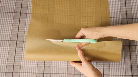Hands holding scissors cut through brown wrapping paper Stock Footage 336480315