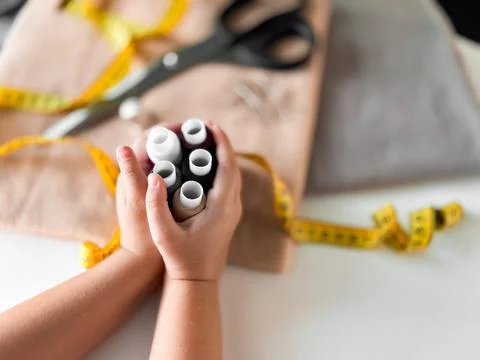 Hands holding sewing threads with scissors and measuring tape in tailoring setup Stock-Fotos