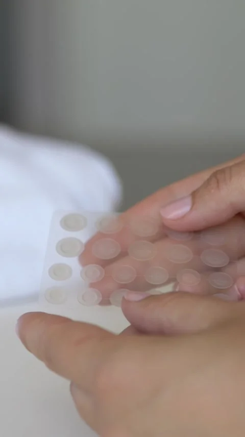 Hands holding sheet of hydrocolloid acne patches on soft neutral background Video stock 336405991