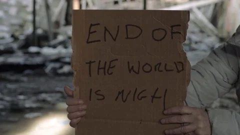 Hands holding sign warning of the end of world in rubble background Video stock 124721780
