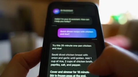 Hands holding smartphone with AI assistant chat asking for dinner recipe Stock Footage 341747288