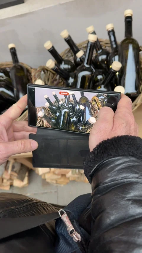 Hands holding smartphone and taking photo of bottles of wine, documenting home Stock Footage 326464665