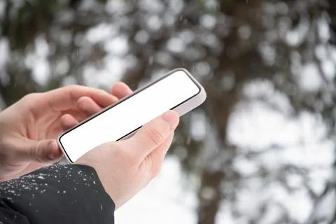 Hands holding smartphone with blank screen outdoors in winter Photos