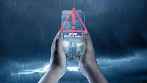 Hands holding a smartphone displaying a red warning alert for stormy weathe.. Stock Illustration