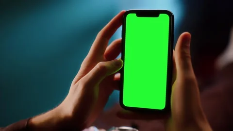 Hands holding smartphone with green screen close-up Stockbeeldmateriaal 319443365