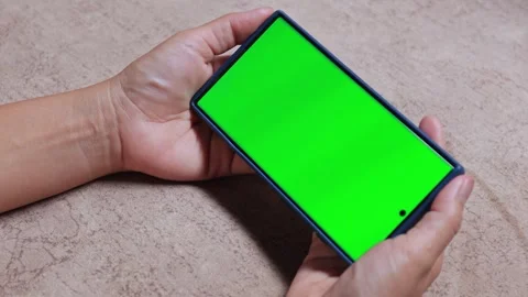 Hands holding a smartphone with green screen in horizontal position Stock Footage 328240979
