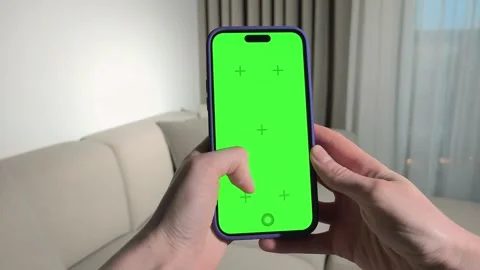 Hands holding smartphone with green screen in living room. Fingers tap and .. Stock Footage 339854797