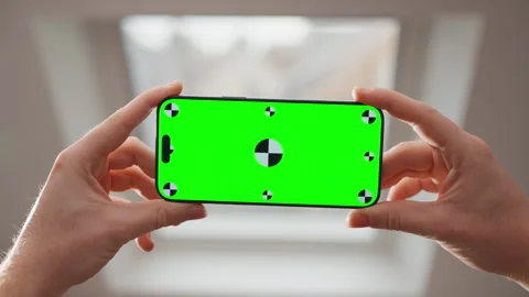 Hands Holding Smartphone with Green Screen Mockup by Window Indoors Stock Footage 345846670
