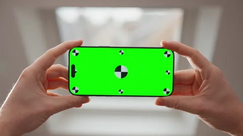 Hands Holding Smartphone with Green Screen Mockup by Bright Window Indoors Stock Footage 345846840