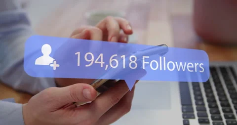 Hands holding smartphone on laptop tapping screen updating follower count for Stock Footage 313295219