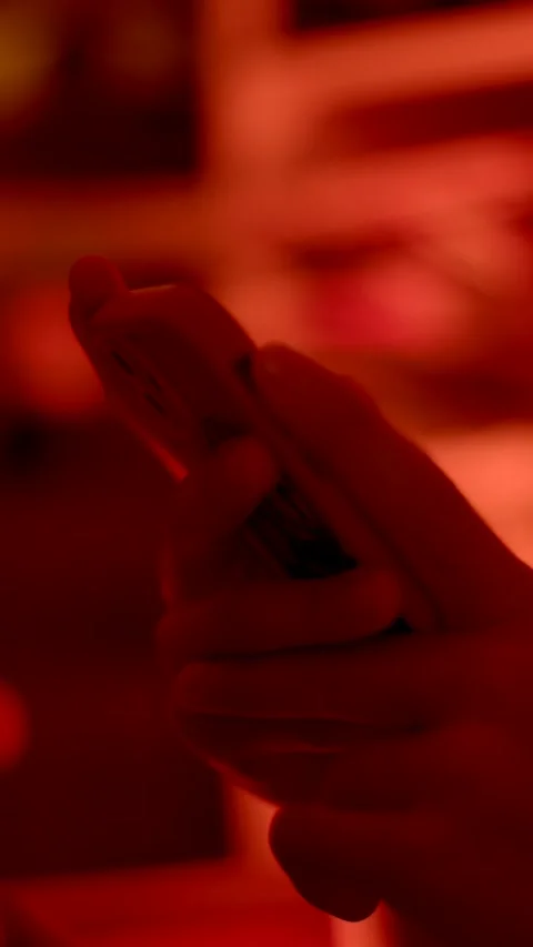 Hands holding smartphone tapping screen in warm red celebration Vidéo 347202765