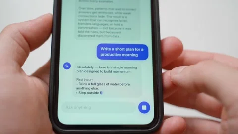 Hands holding smartphone typing prompt about productive morning plan to AI Stock Footage 342129701