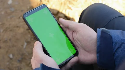 Hands holding smartphone in vertical position touching phone with green screen Stock Footage 194956605