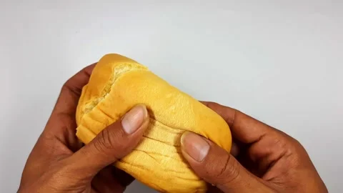 Hands holding soft sweet bread roll filled with yellow cream filling Stock Footage 325974057