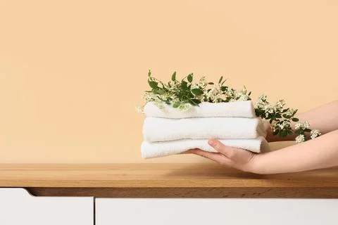 Hands holding a stack of clean white towels with fresh green branches and sma Stock Photos