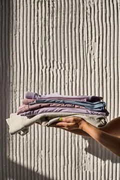Hands Holding a Stack of Folded Clothes Stock Photos